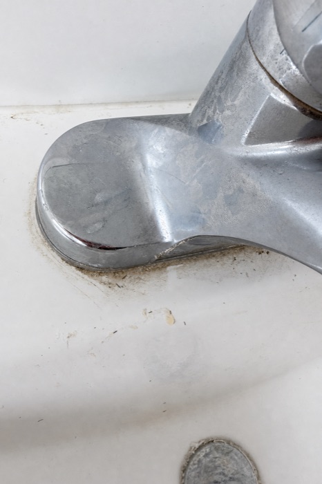 Chrome bathroom faucet with grime and water spots before a NeatNow clean in Calgary