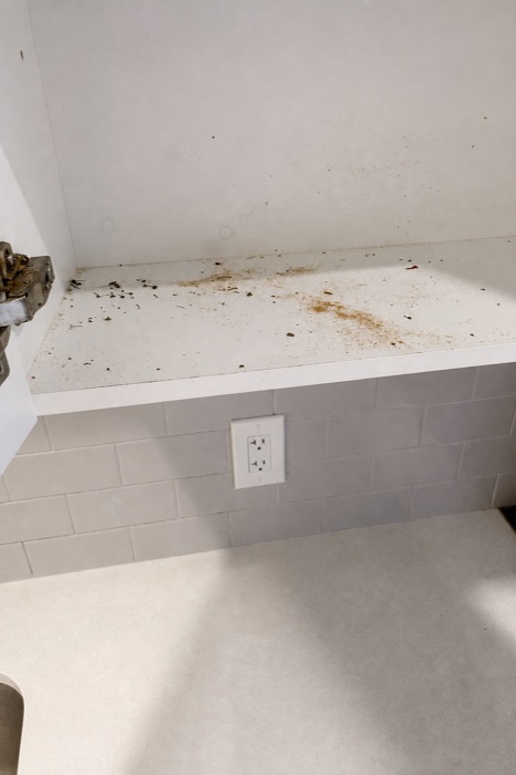 White shelf scattered with debris and stains before a NeatNow clean in Calgary