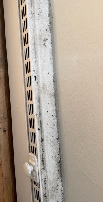 Baseboard heater vent caked with dust and grime before a NeatNow clean in Calgary